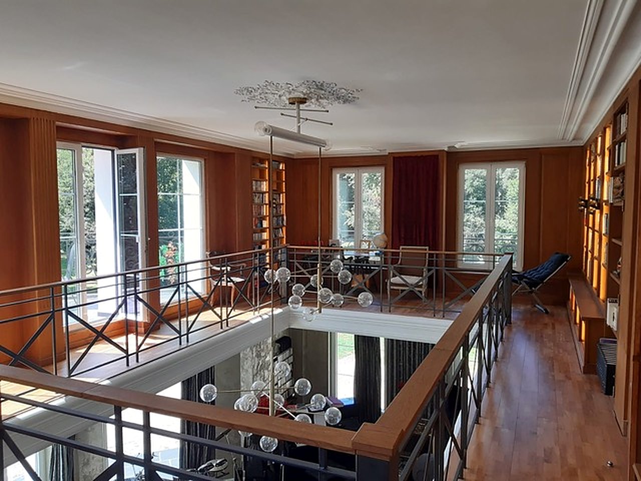 Bibliothèque en mezzanine, boiseries chaudes et double hauteur ouverte sur le salon